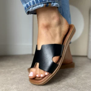 Czarne skórzane klapki LULA 11 na stopach kobiety w niebieskich jeansach – widok z przodu.