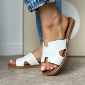 Białe skórzane klapki LULA 11 na stopach kobiety w niebieskich jeansach – widok z przodu.