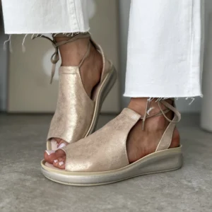 Skórzane złote sandały damskie LULA 08 z odkrytymi palcami i sznurowaniem wokół kostki, wykonane w polskiej produkcji, prezentowane na stopach w białych spodniach na tle jasnej podłogi.