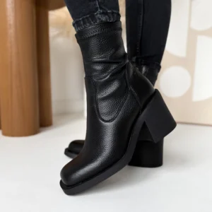 Czarne botki skórzane LULA 140 na stabilnym 7-centymetrowym obcasie typu klocek, wykonane z naturalnej skóry licowej typu groszek, prezentowane na nodze w stylizacji z czarnymi jeansami.