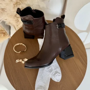 Brązowe botki damskie LULA 160 wykonane ze skóry naturalnej, na stabilnym czarnym słupku z ozdobnym paskiem i klamrą, prezentowane na nodze.