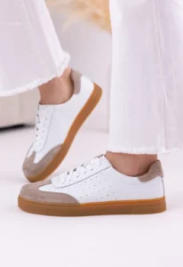 Skórzane trampki damskie LULA 51 w kolorze białym z beżowymi zamszowymi wstawkami i gumową podeszwą, na nodze modelki w białych spodniach